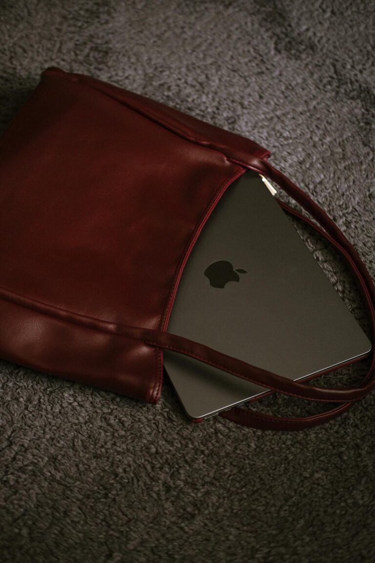 A sleek leather bag partially revealing a modern laptop on textured surface.