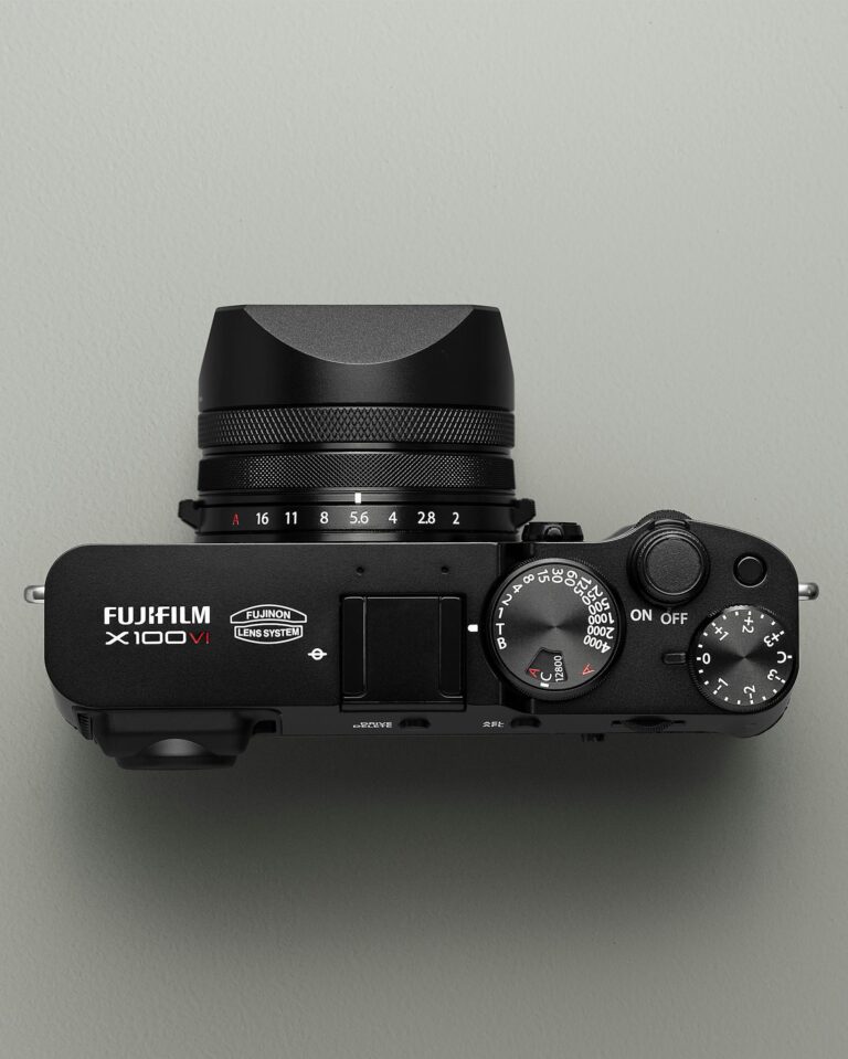 Minimalist top view of a modern Fujifilm X100V camera against a neutral background.